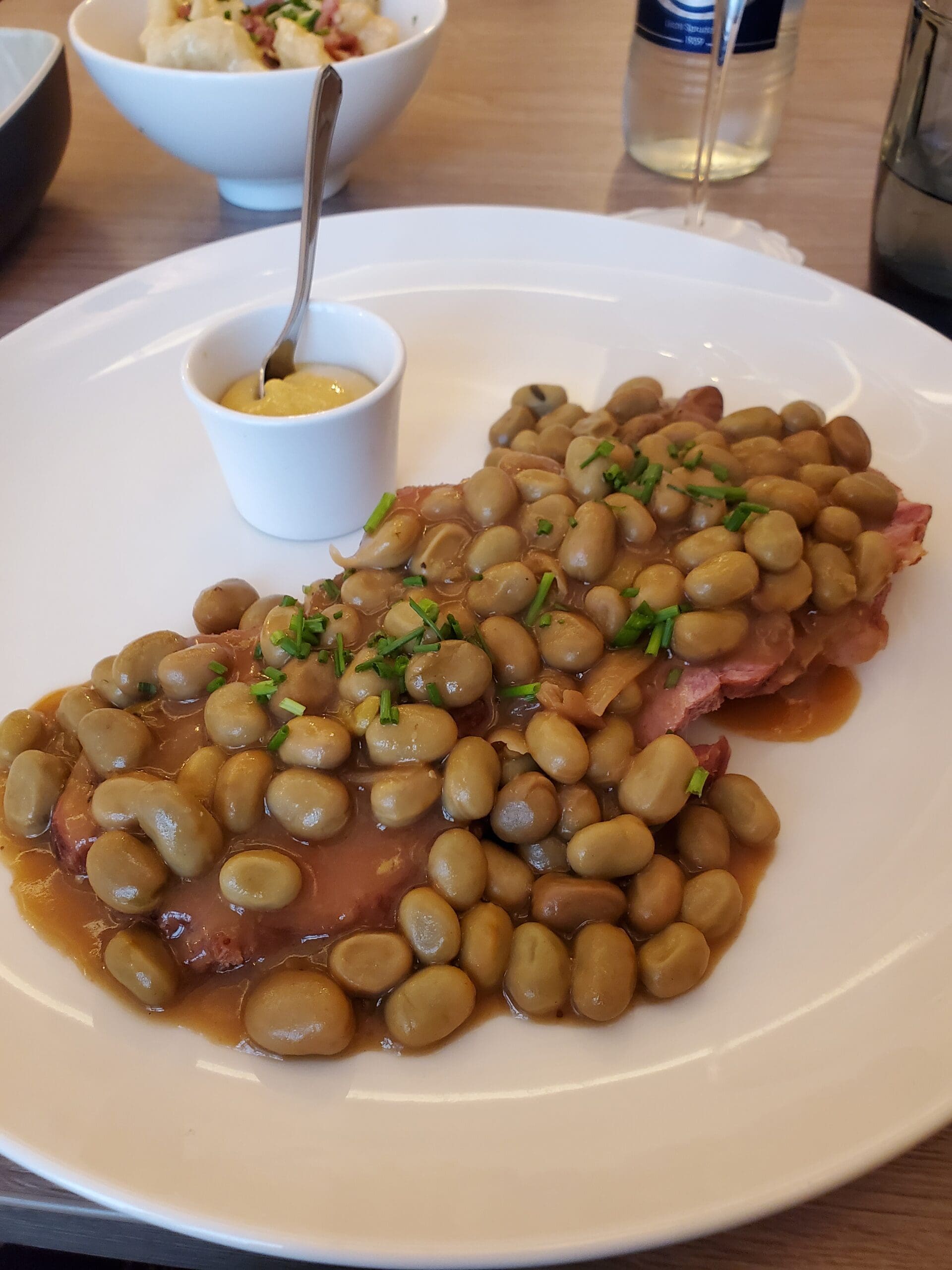 Judd mat Gaardebounen, Pork Neck and Broad Beans on a white plate with Luxembourgish Mustard as a side