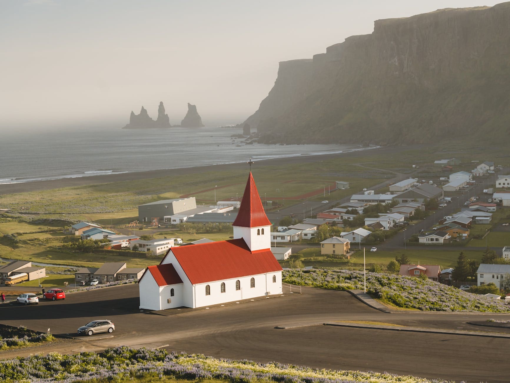 A small, seaside village in Iceland with a red and white church in the foreground. Small villages are great places to find authentic Icelandic food.