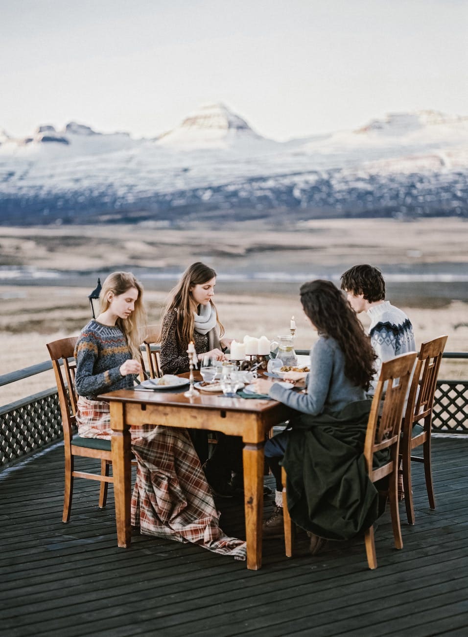 young friends sitting at table on terrace and having dinner together