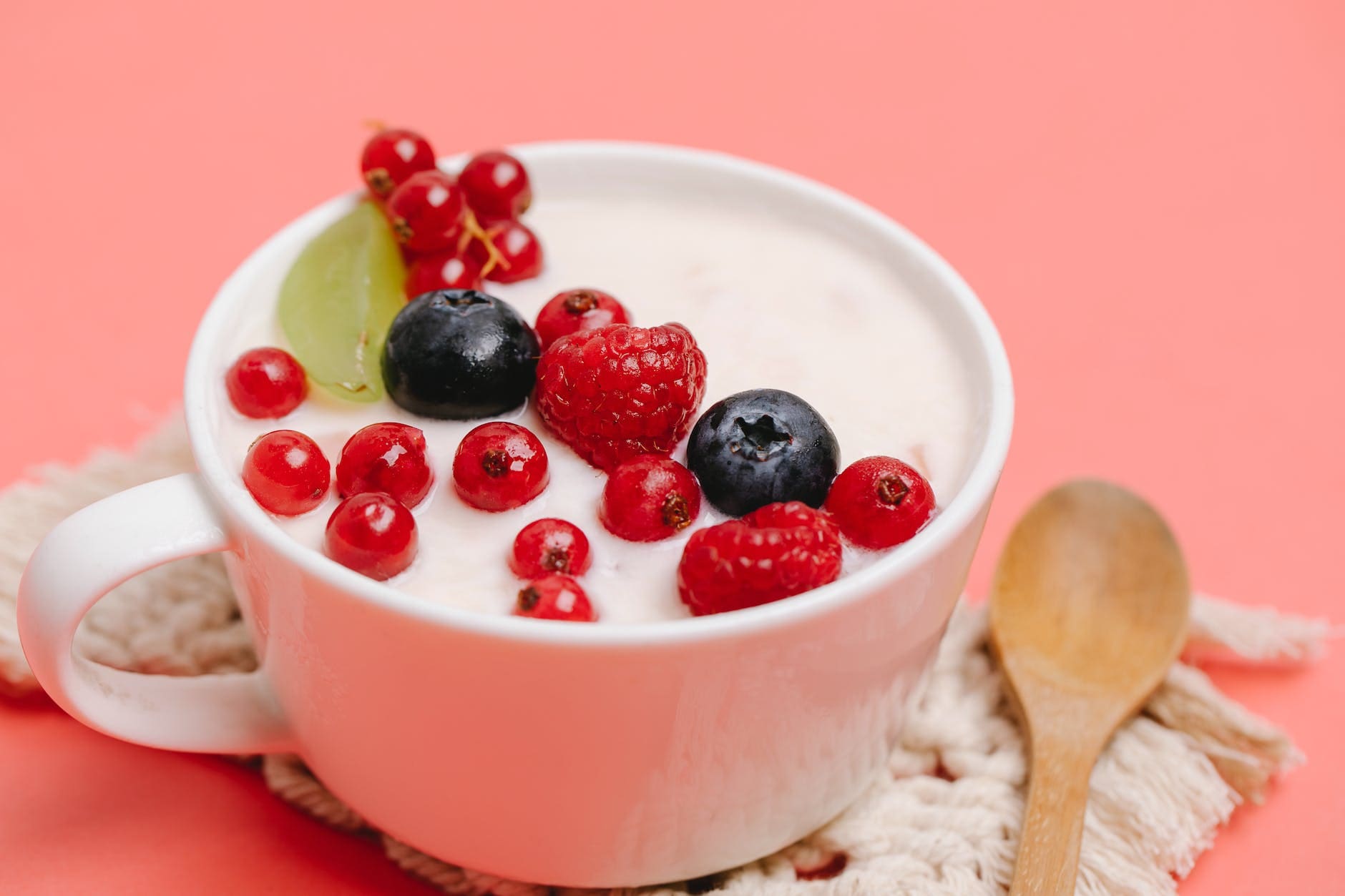 tasty healthy dessert with berries served on pink table with wooden spoon