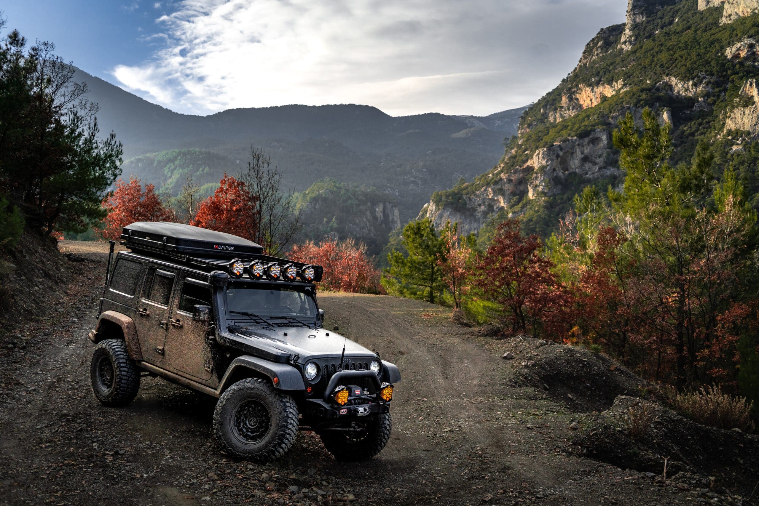 iKamper Mini Rocky Black on an overlanding jeep on a gravel road in the mountains.