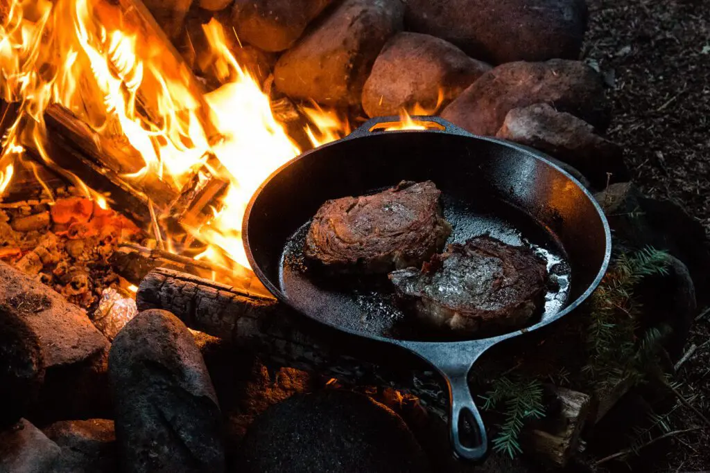 Steak grilling in a cast iron on the fire