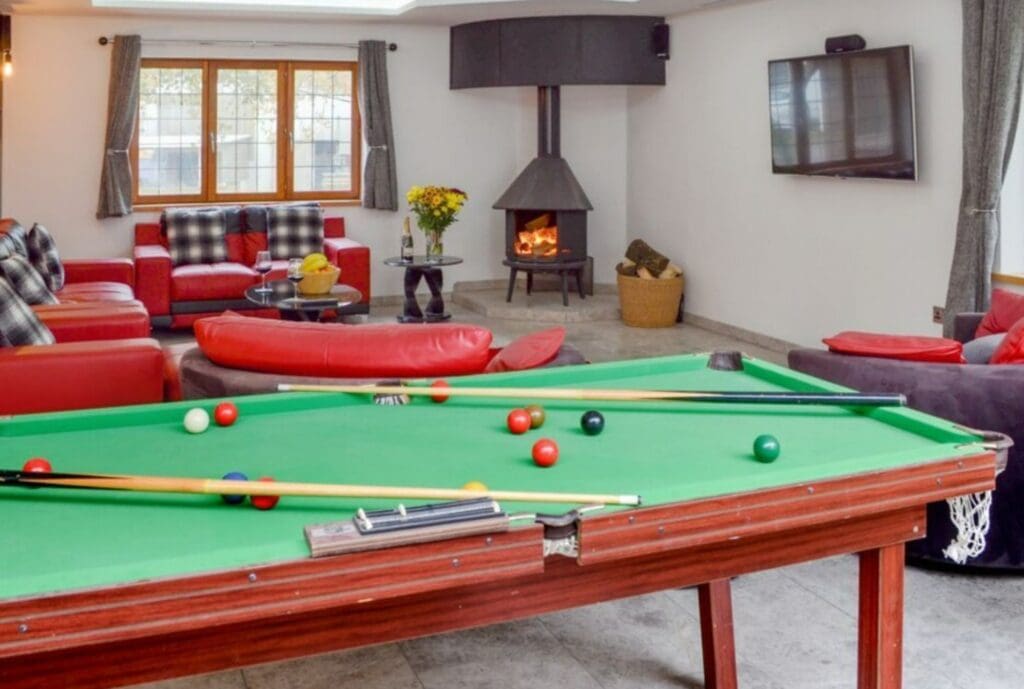 Game room with red couches, billiards, and a fire