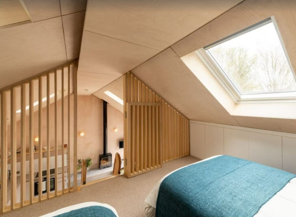 A bedroom loft looking down at a fireplace, living room, and kitchen
