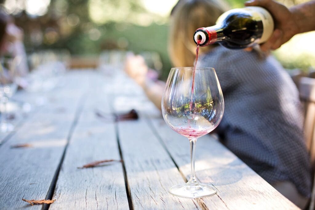 Red Wine being poured into a glass on a picnic table